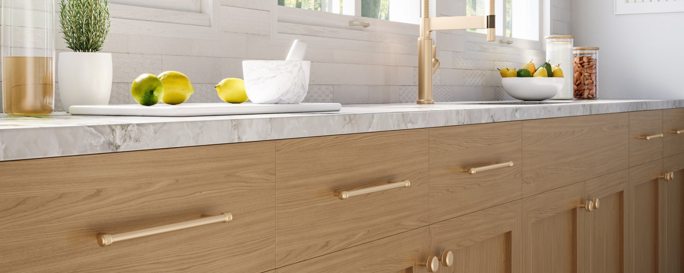 Oak kitchen cabinets with Top Knobs Elland bar pulls and knobs in Honey Bronze along a marble counter