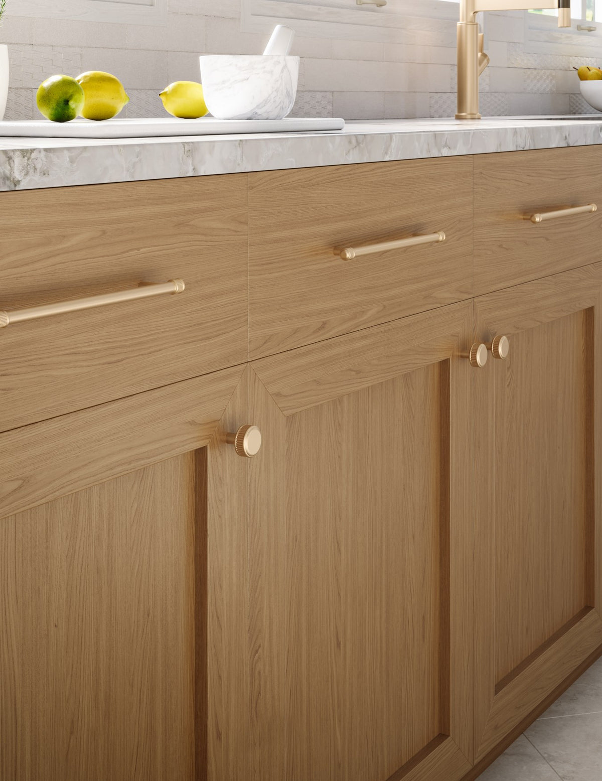 Top Knobs Elland bar pulls and knobs in Honey Bronze on oak cabinetry below a marble counter
